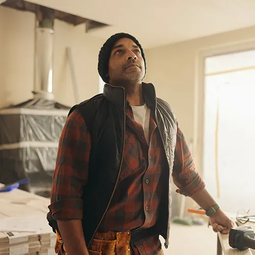 687849717 Mature builder standing in living room, pensive and contemplating home renovation ideas